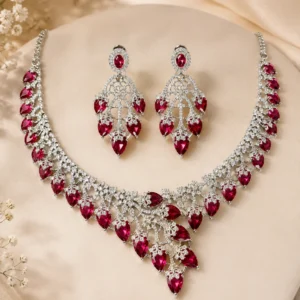 Deep Ruby Royale rhodium-plated CZ necklace set with maroon pear-shaped stones and matching earrings on a cream display